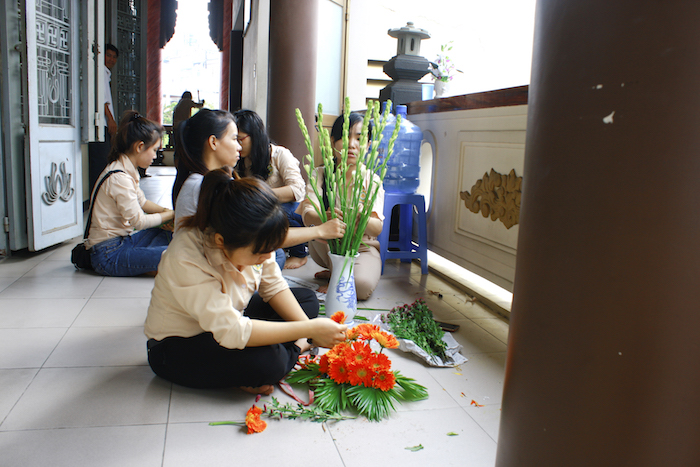 Nhóm bạn phụ trách cắm hoa bàn Phật và bàn Giảng sư.